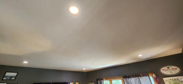 Upward view of a curved white ceiling with recessed lights in a living room