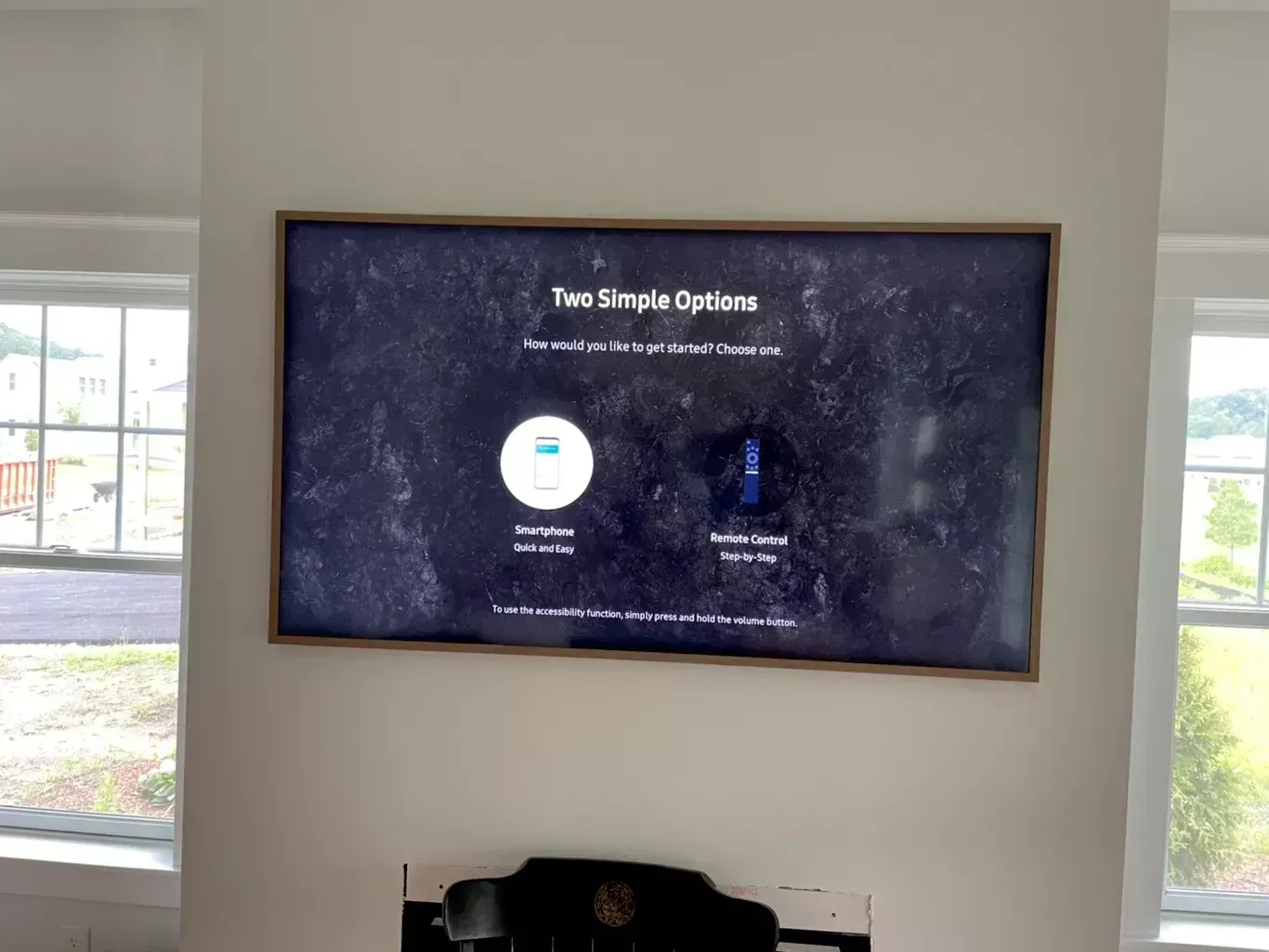 Wall-mounted TV showing “Two Simple Options” in a bright room with windows and a chair below.