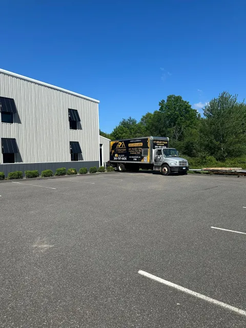 A silver truck parked next to a modern building. Clear blue sky.