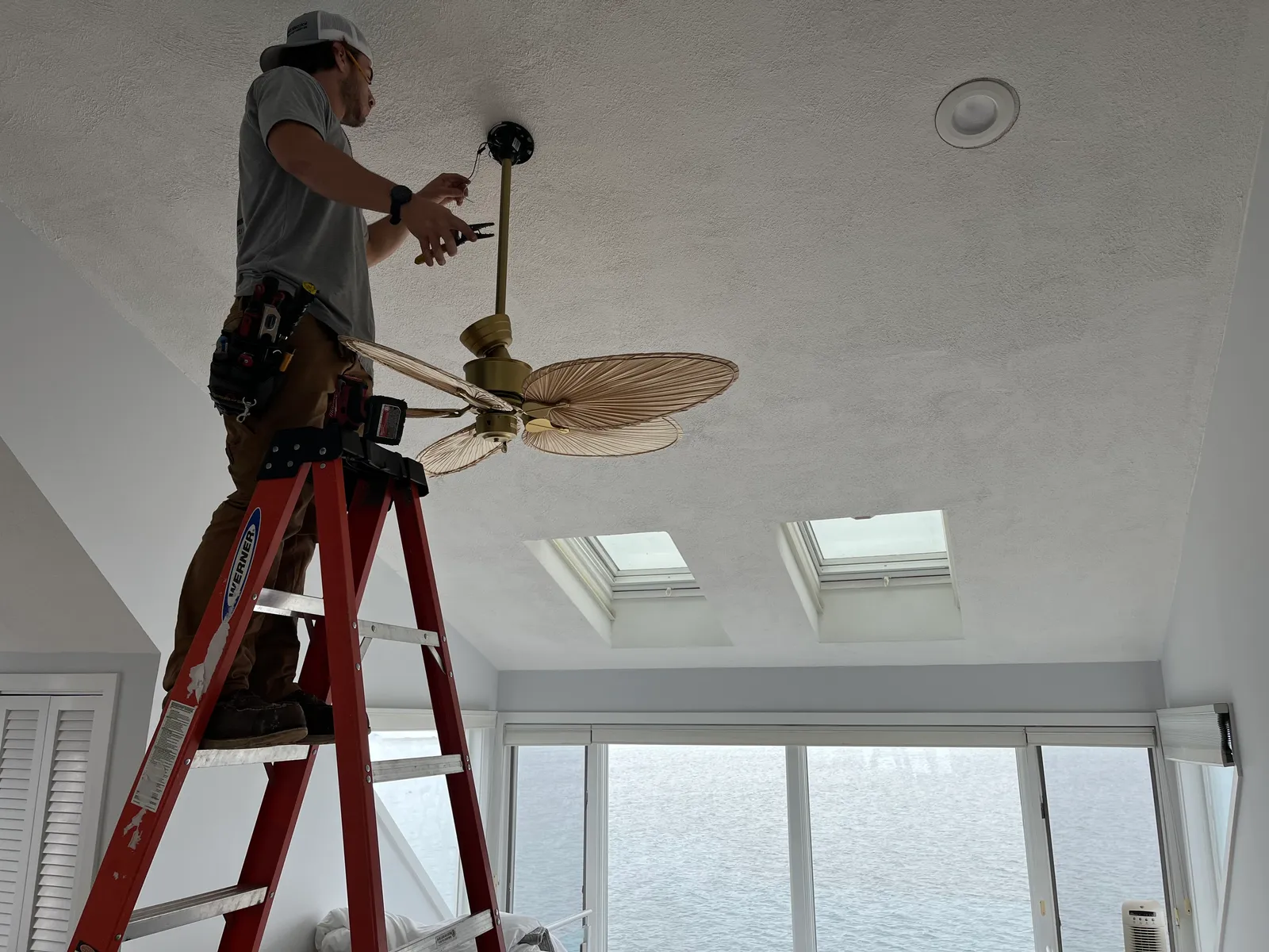 Electrician installing a ceiling fan