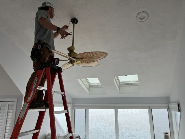 Electrician installing a ceiling fan