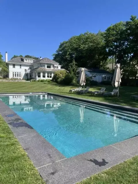 picture of a pool in front of a white mansion