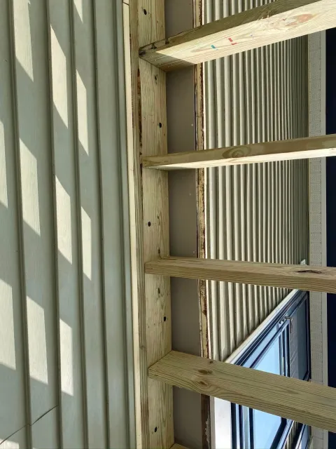 A close up of a wooden structure with a window in the background.