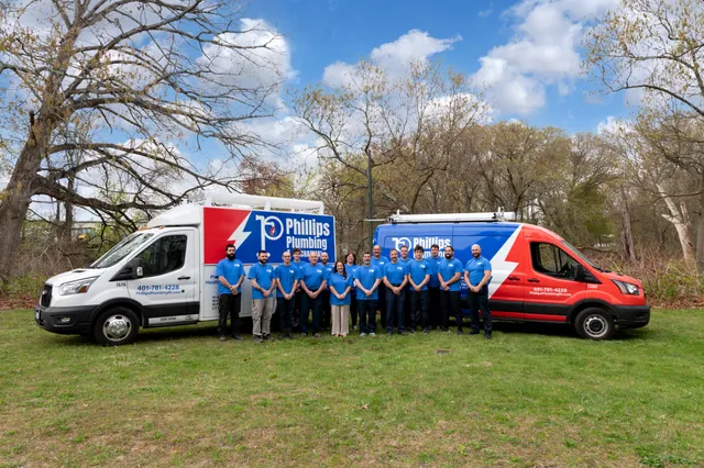 The Phillips Plumbing and Mechanical team standing between two of their service vans