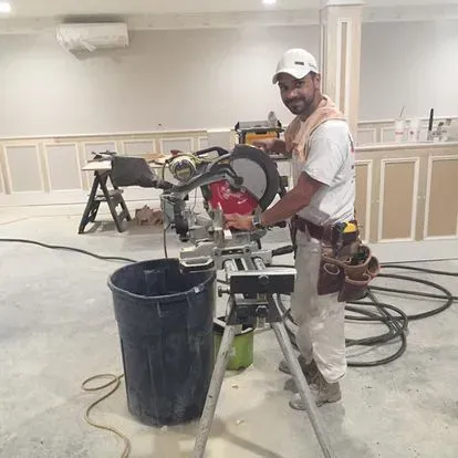 A man is standing next to a circular saw in a room.