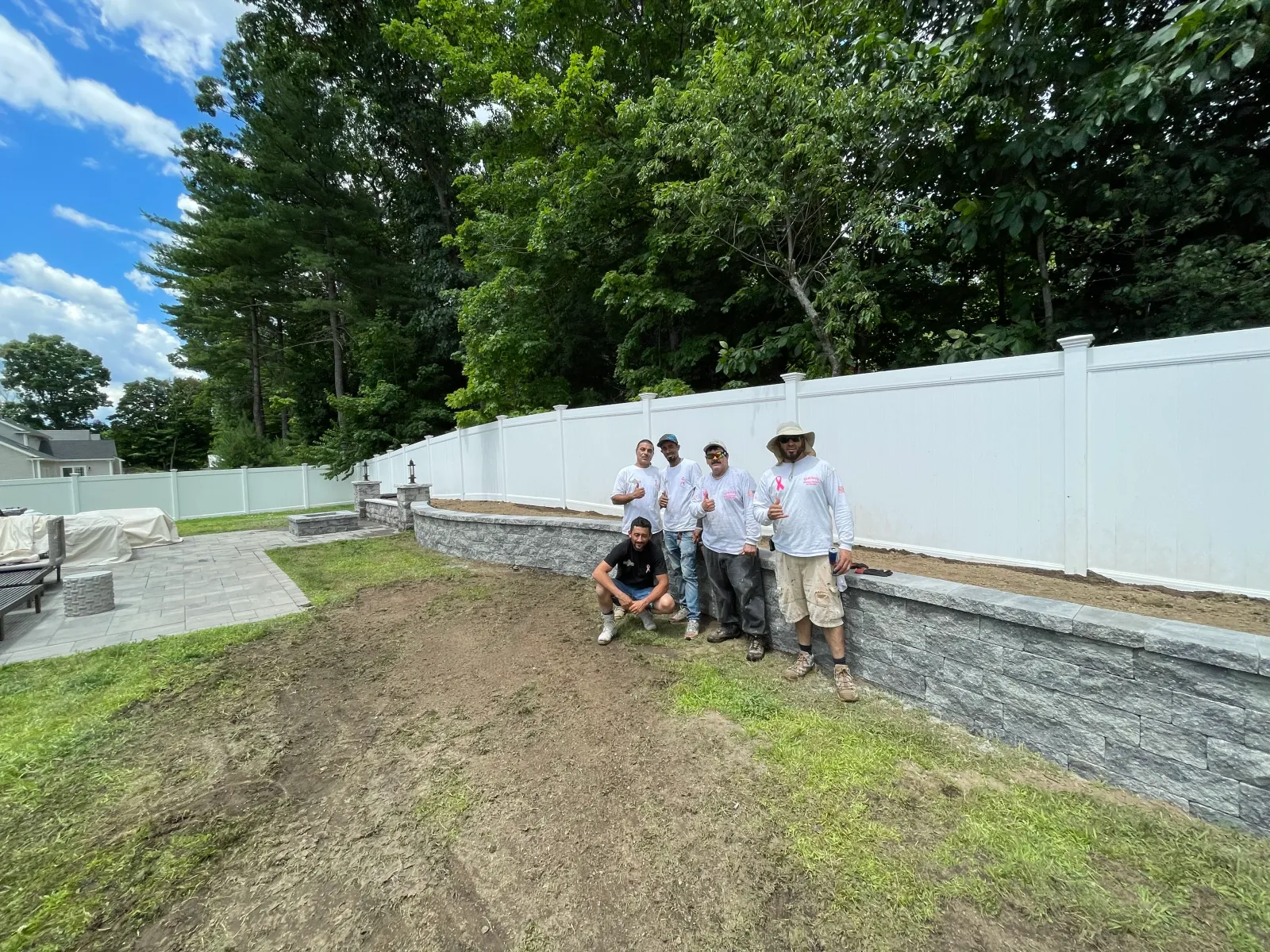 New vinyl fence and retaining wall along a regraded yard