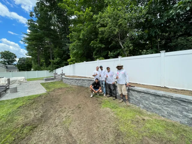 New vinyl fence and retaining wall along a regraded yard