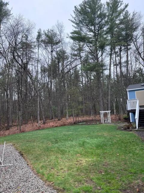 A house with a large lawn in front of it and trees in the background.
