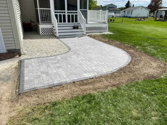 A walkway is being built in front of a screened in porch.