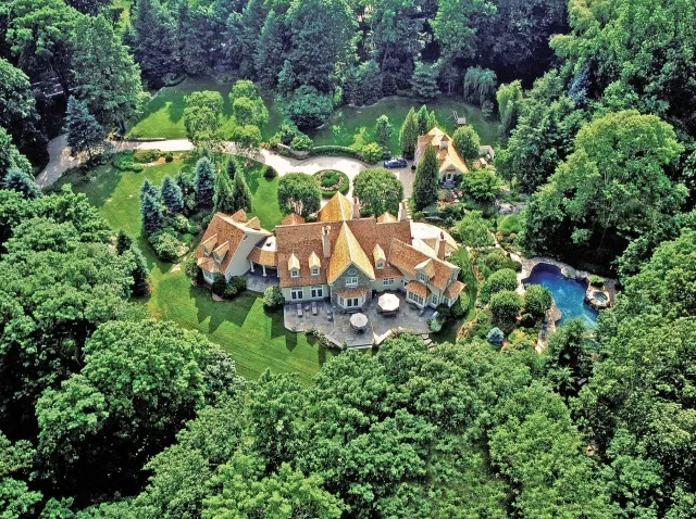 Wide aerial view of a finished residential roof and wooded property