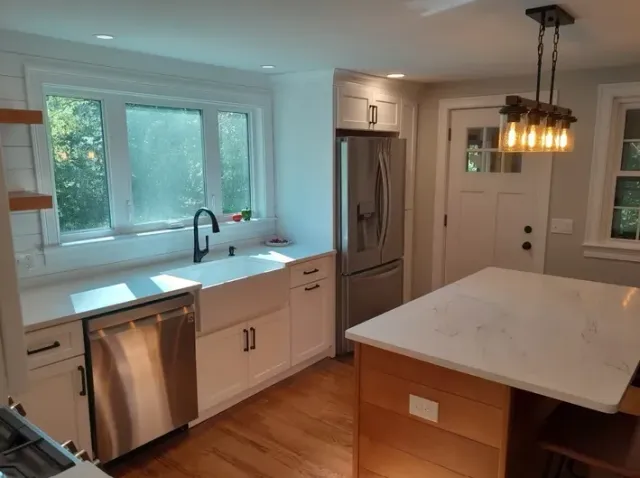 A kitchen with white cabinets, stainless steel appliances, and a large island.