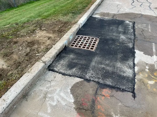 A manhole cover is sitting on the side of a road next to a curb.