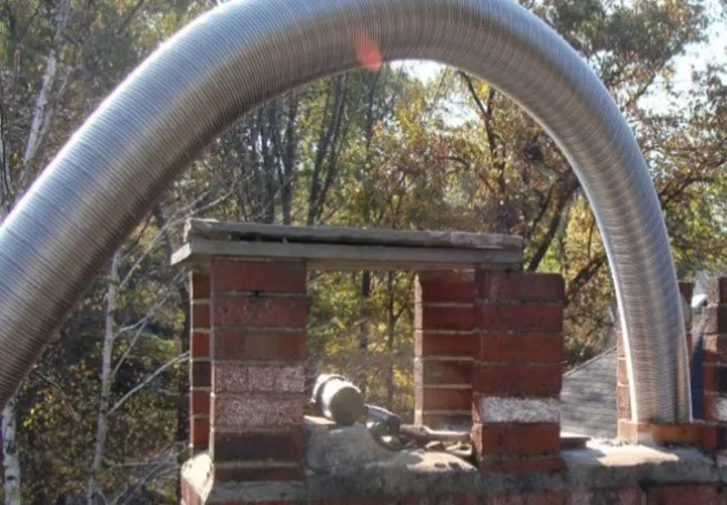 A flexible stainless steel chimney liner being installed into a brick chimney by Northeast Chimney Sweeps for home safety.