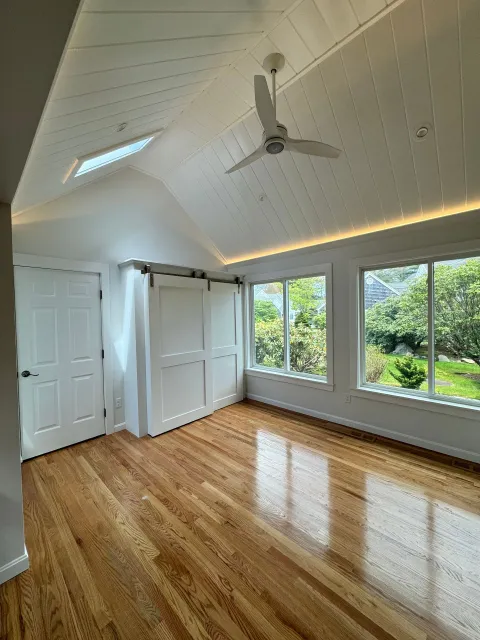 An empty room with hardwood floors and a ceiling fan