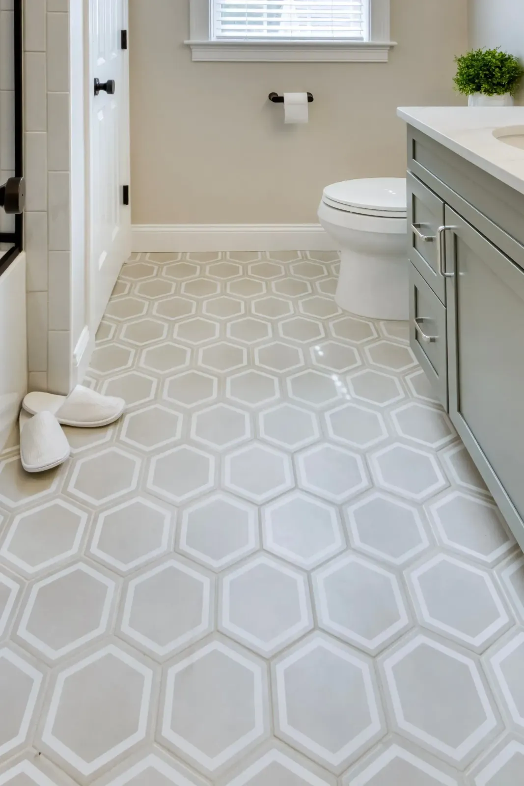 Small bathroom with patterned floor tiles, white toilet, vanity, and window.