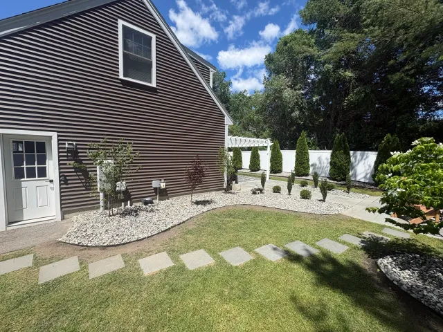 Completed landscape renovation featuring steel edging, plantings, and decorative stone in Greenland, NH.