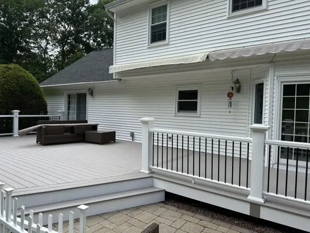 white-house-with-large-gray-deck-and-black-metal-railing-outdoor-steps.webp