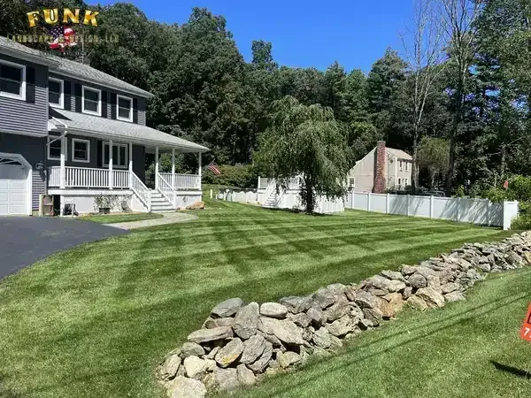 Freshly striped front lawn wrapping around a natural stone wall