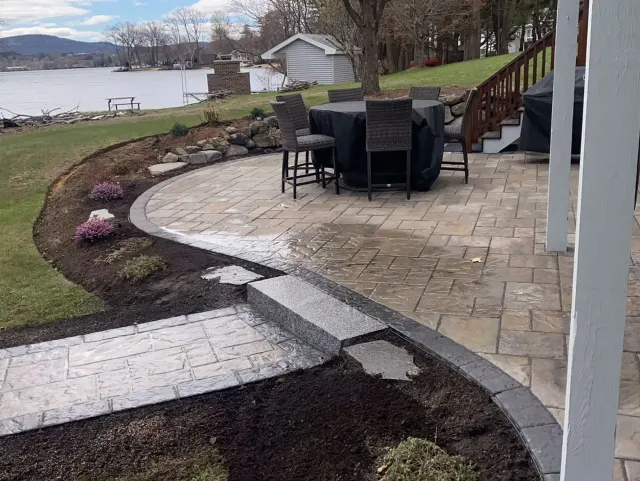 A patio with a table and chairs and a view of a lake.