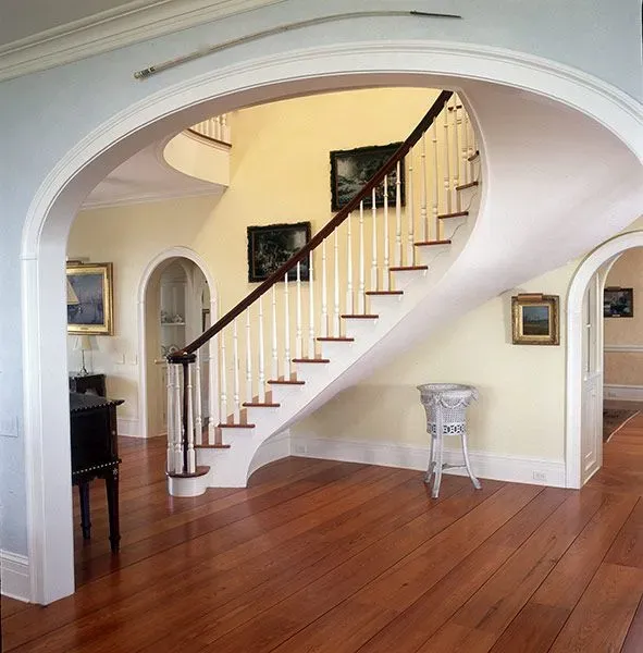 A curved staircase in a house with a wooden floor