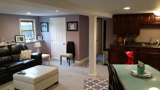 A living room with a couch , ottoman , table and kitchen.