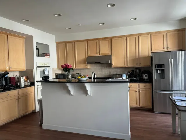 outdated kitchen with beige cabinets and black countertops