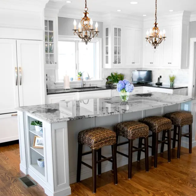 Modern kitchen with white cabinets, gray marble countertops, and dark wicker bar stools.