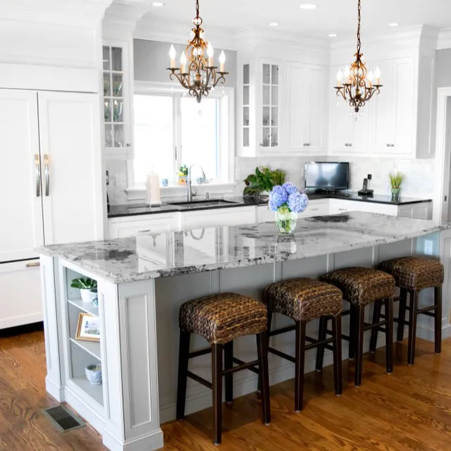 Modern kitchen with white cabinets, gray marble countertops, and dark wicker bar stools.