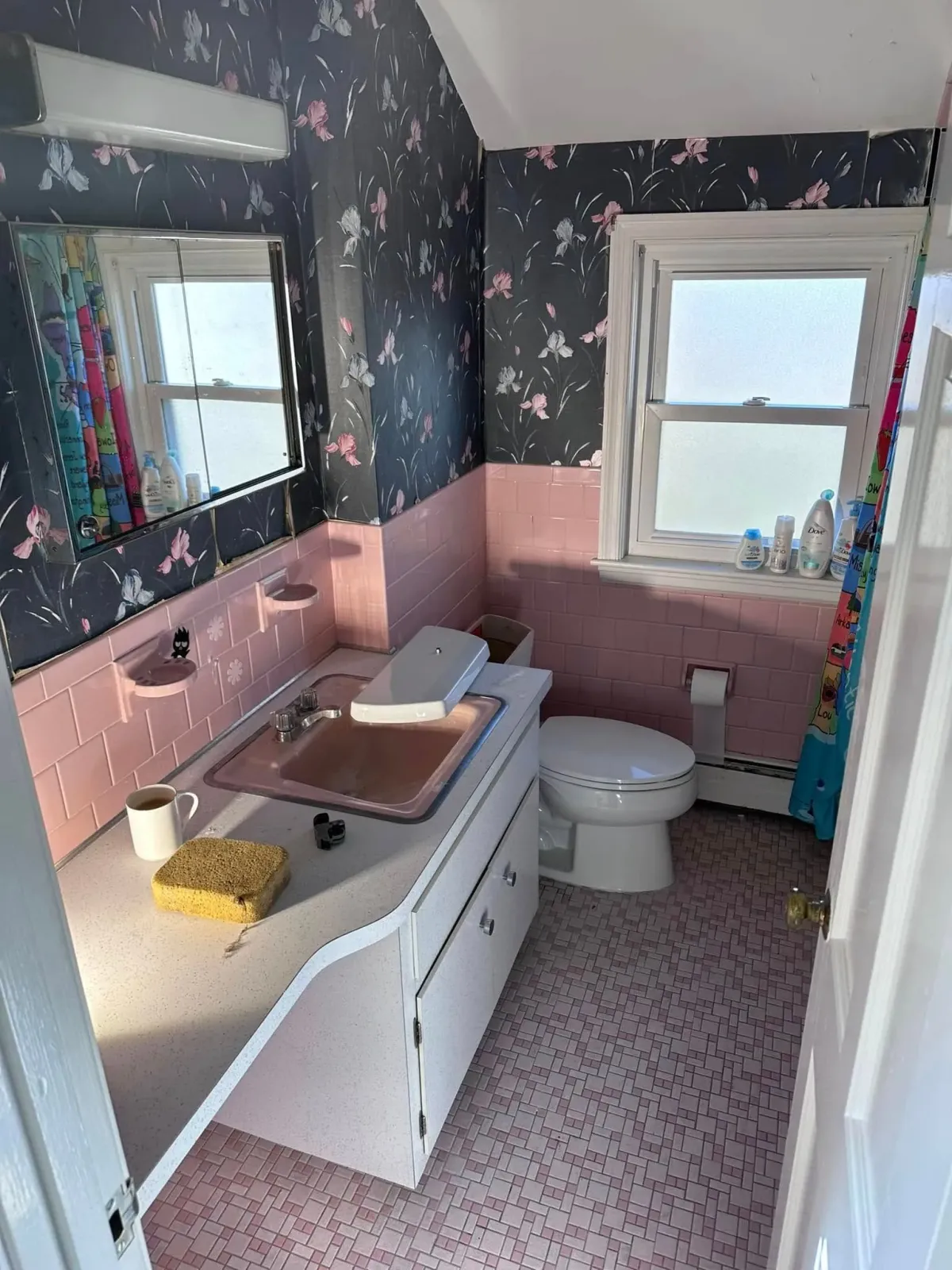 A bathroom with a sink, toilet, and mirror.