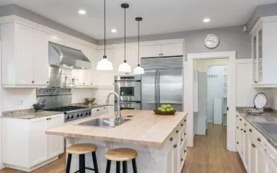 A kitchen with white cabinets , stainless steel appliances , a sink , and a large island.