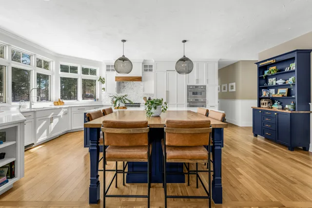 Wide view of a Norwell kitchen with white perimeter cabinetry and a deep navy island