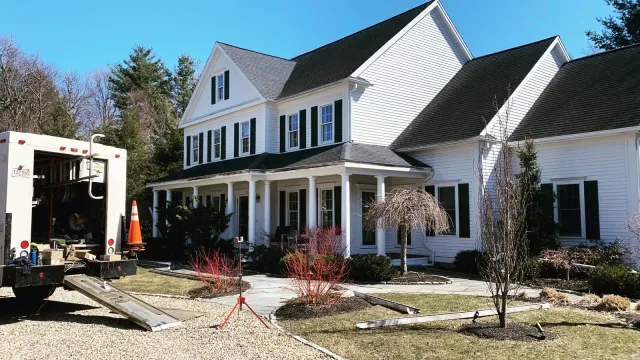 Large white colonial home with B.A. Harris work truck parked during gutter work
