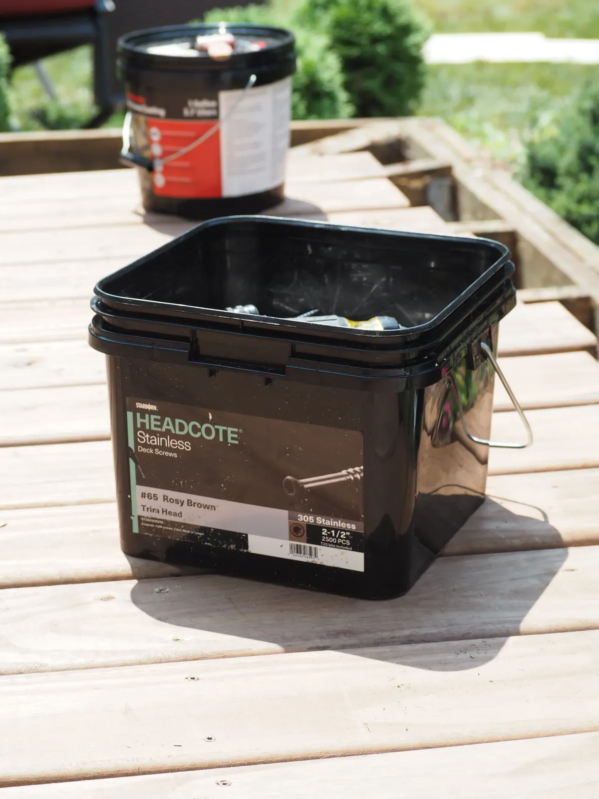 Container of stainless steel deck screws on wooden outdoor table