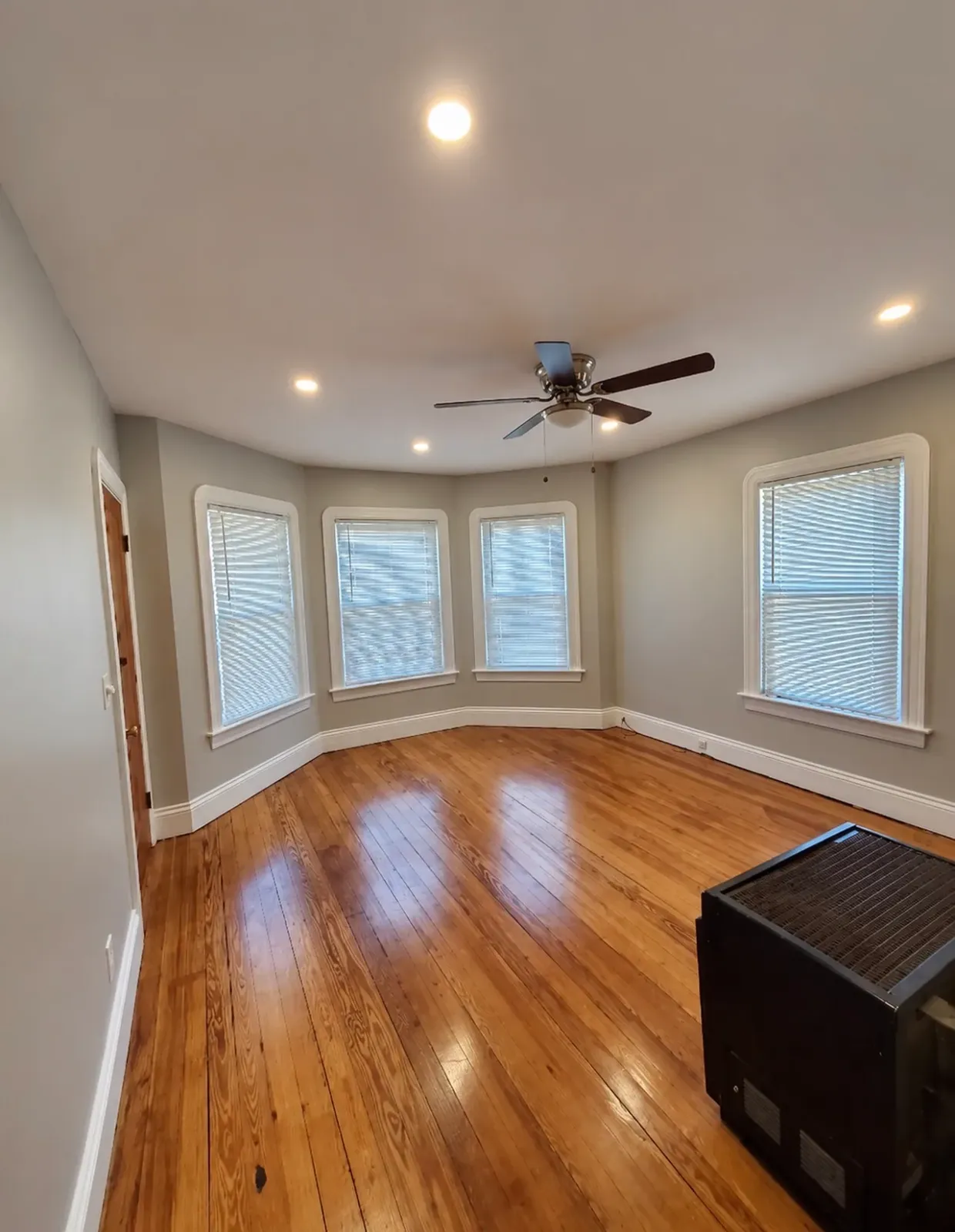 Bay-window room with recessed lighting, a ceiling fan and wood flooring.