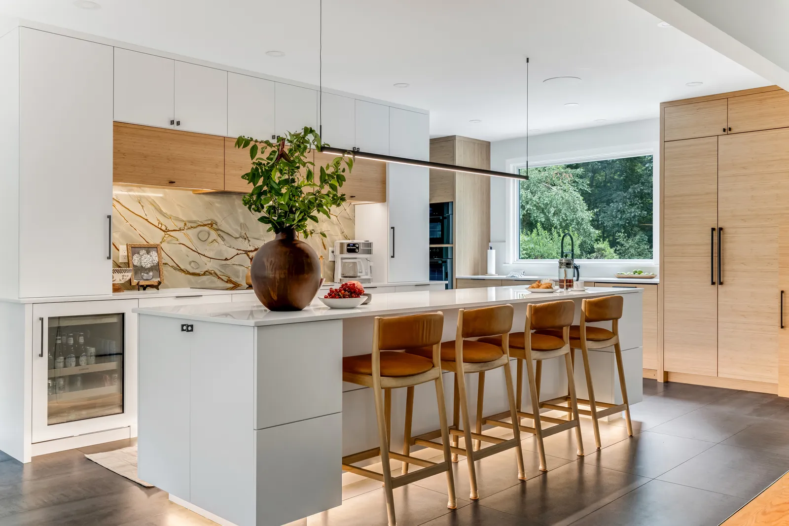 Modern Marshfield kitchen remodel with white high-gloss cabinets, quartz island, leather stools, and a gold-veined granite slab backsplash