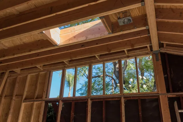 Interior of a house under construction, showing exposed wooden framing and a skylight opening.