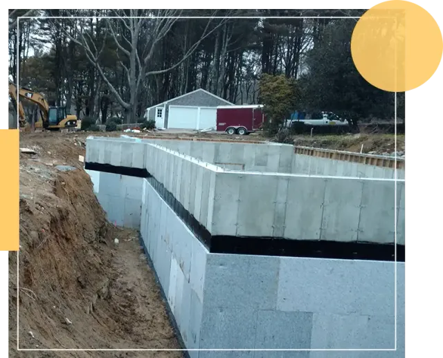 The image shows a construction site with a concrete foundation in progress, excavation equipment, and a small white building in the background.
