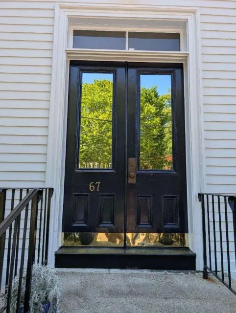 Black double doors with reflective glass panels; gold kick plate,