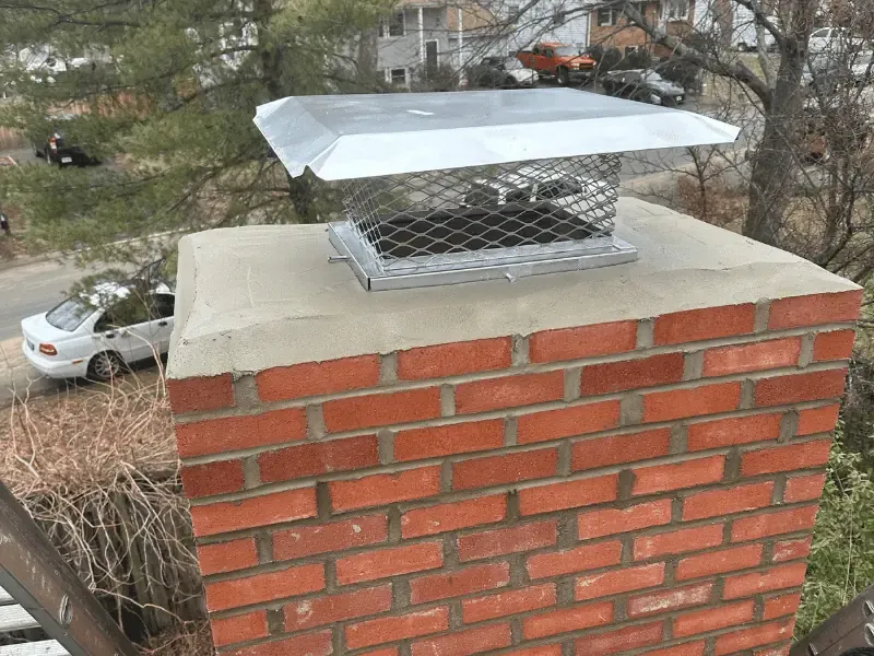 Stainless steel chimney cap installed on brick chimney