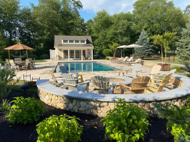 Stone patio and rounded retaining wall with plantings and mulching
