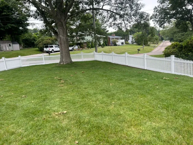 A white picket fence surrounds a lush green yard.