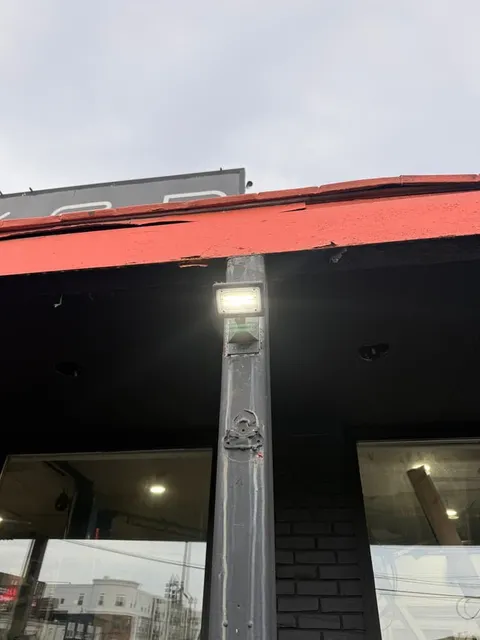 An LED wall pack lighting a storefront entry for a Manchester-area business.