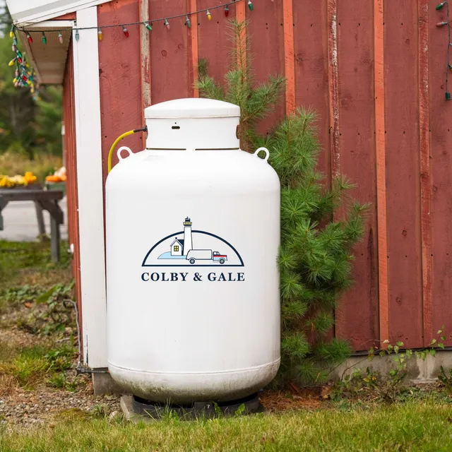 A propane tank featuring the blue and white Colby & Gale logo, serving a home in the Midcoast Maine region.