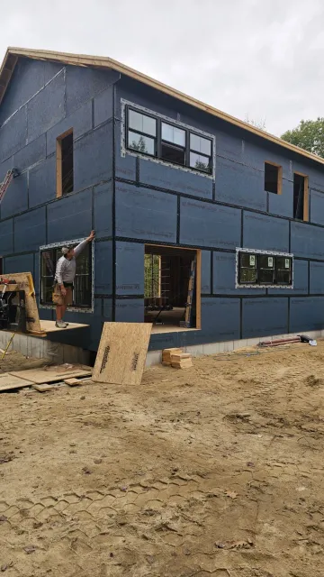 A blue house is being built in a dirt field.