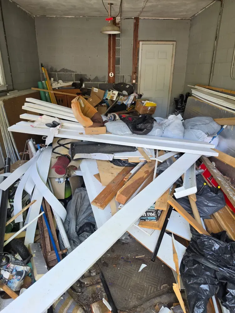 A garage packed with lumber and debris before a Pioneer Valley Junk Removal cleanout