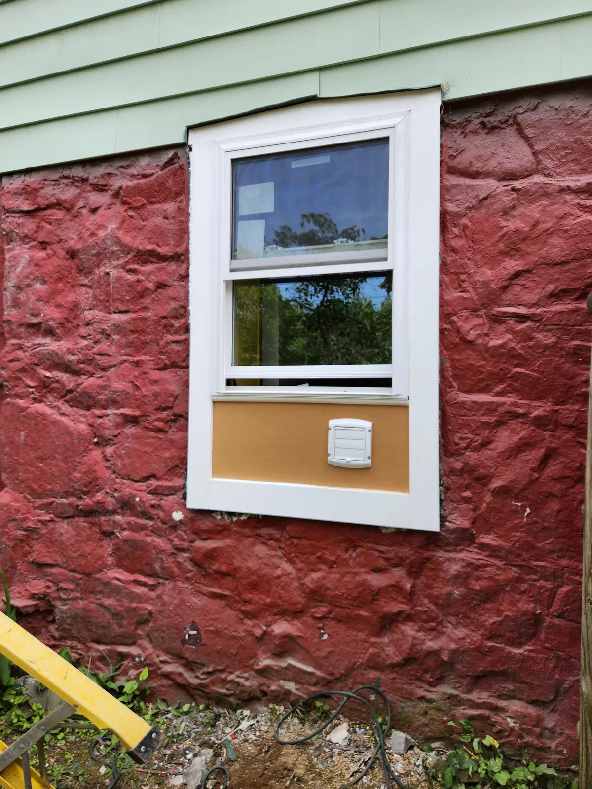 Exterior window replacement on a painted stone foundation wall