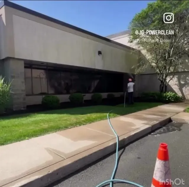 A man is standing in front of a building with a hose attached to it