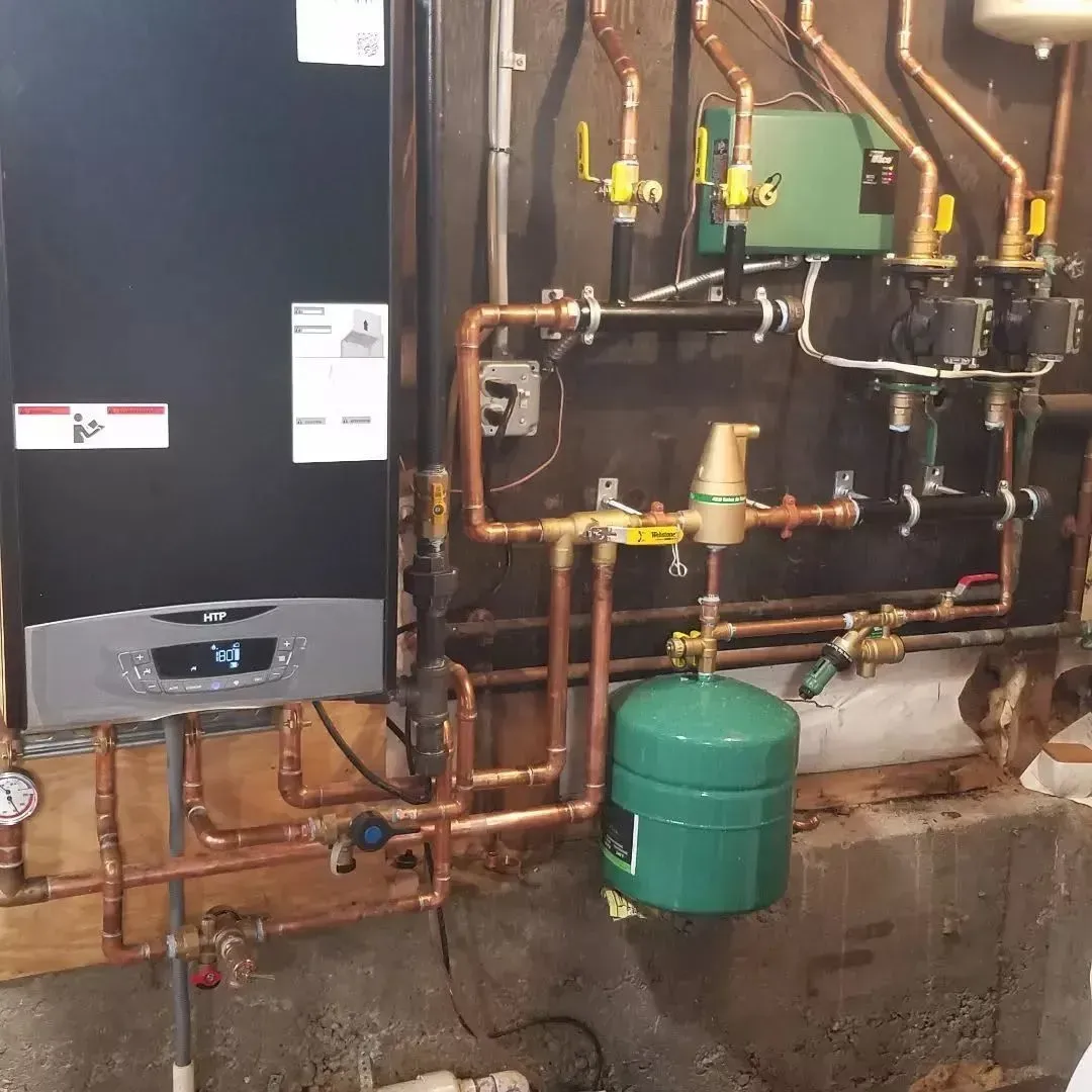 Boiler room with copper pipes, green expansion tank, and heating equipment mounted on a basement wall