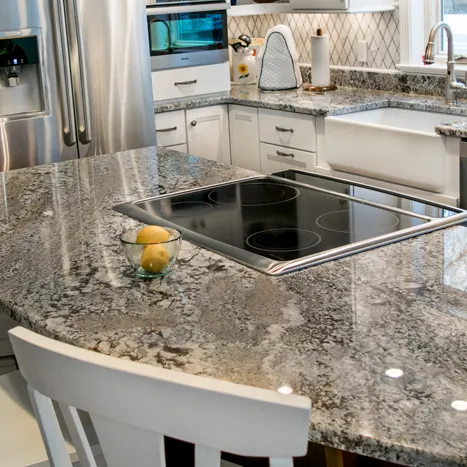 Modern kitchen with gray granite countertops and white cabinets.