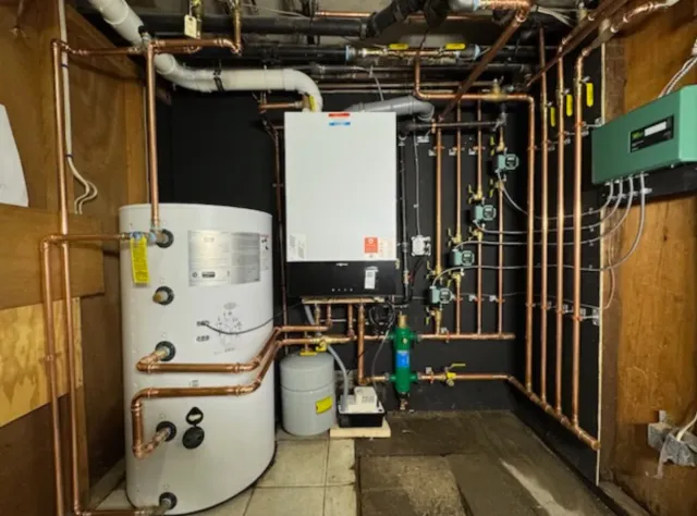 A boiler room with copper pipes, a water heater, and various mechanical components.
